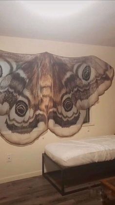 a large butterfly is hanging on the wall above a bed