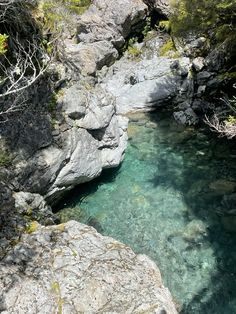 the water is crystal blue and clear in this rocky area with trees on both sides