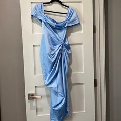 a blue dress hanging on a door with a hanger in front of it that has a knoted neckline