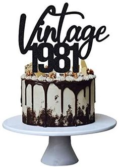 a black and white cake with the words vintage 1950 on it, sitting on a plate