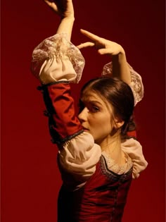 a woman in a red and white dress holding her arms up to the side with one hand