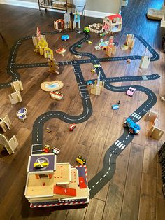 toy cars and trucks are on the floor in front of a play set with wooden blocks