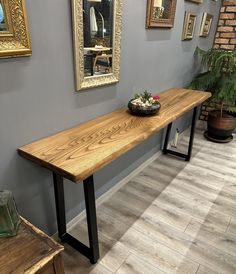 a wooden bench sitting next to a potted plant on top of a hard wood floor