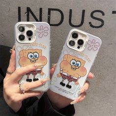 two people holding up cell phones with cartoon characters on them