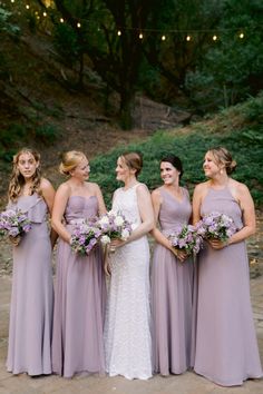 a group of women standing next to each other wearing dresses and holding bouquets in their hands