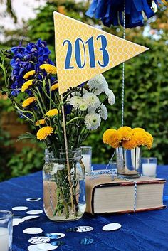 a table topped with vases filled with yellow and white flowers next to an open book