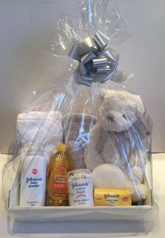 a teddy bear wrapped in plastic and surrounded by baby products, such as milk, soaps, and lotion