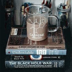 three books stacked on top of each other next to a glass mug filled with liquid