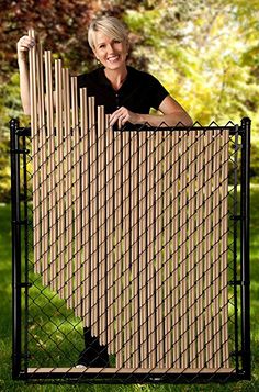 a woman standing behind a fence with her hands on the top of it and smiling at the camera