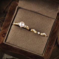 a pair of pearl and diamond brooches in a wooden box on the ground