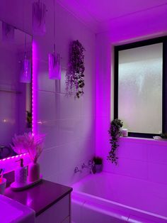 the bathroom is lit up with purple lighting and plants in pots on the window sill