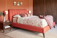 a bedroom with an orange bed and pink accents on the walls, along with two nightstands