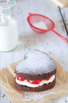 a chocolate sandwich with cream filling and powdered sugar on the table next to it