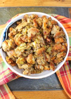 a bowl filled with stuffing sitting on top of a table next to an orange and white towel