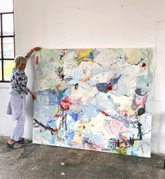 a woman is painting on the wall in an art studio