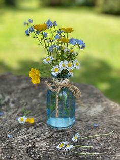 a glass vase filled with flowers on top of a wooden table next to some grass