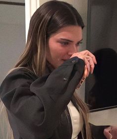 a young woman brushing her teeth in front of a bathroom mirror while looking into the mirror