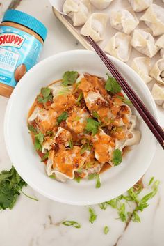 a white bowl filled with food next to chopsticks