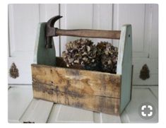 an old wooden toolbox with pine cones in it and a hammer sticking out of the top