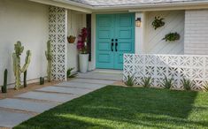 a house with a blue front door and cactus plants in the grass next to it