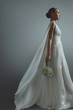 a woman in a white wedding dress holding a bridal bouquet and looking off to the side