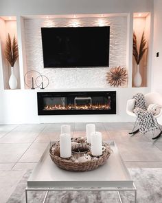 a white living room with a fireplace and television above the fire place in front of it