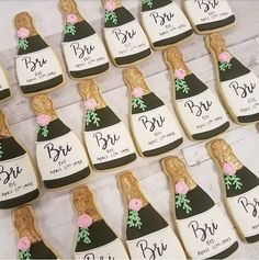 decorated cookies in the shape of wine bottles with flowers on them for bridal party