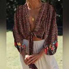 This Flowy Crop Top Is Perfect For Any Occasion, From A Day At The Festival To A Night Out With Friends. This Is A Very Versatile Piece That Can Be Worn As A Festival Top, Blouse, Wrap Top, Crop Top, Tie Front Top, Or Boho Blouse. Dress It Up With A Pair Of Your Favorite Jeans Or Skirt For An Effortless Casual-Chic Look! Boho Crop Top Deep Plunging V-Neck Long Sleeves Self-Tie Front Closure Short, Cropped Length Soft, Lightweight Fabric Measurements Are Approximate: Size Small Measurements: Bust Boho Tie Front Top, Black Boho Print Tops For Spring, Spring Black Boho Print Tops, Black Floral Print Vacation Blouse, Black Bohemian Blouse With Floral Print, Black Floral Print Festival Blouse, Black Floral Print Blouse For Festival, V-neck Floral Print Top For Festival, Festival Floral Print V-neck Top