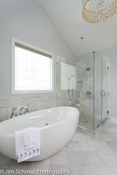 a large white bath tub sitting in a bathroom next to a walk - in shower