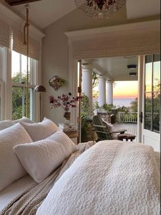 a large bed sitting in a bedroom next to a window covered with white sheets and pillows