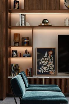 a blue couch sitting in front of a wooden book shelf filled with books and art