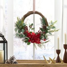 a christmas wreath on a window sill with candles