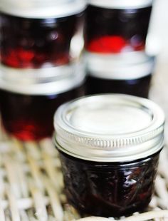 several jars filled with jam sitting on top of a woven table cloth next to each other