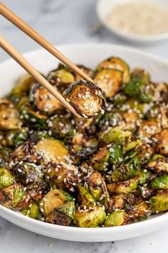 a white bowl filled with brussel sprouts and topped with sesame seeds