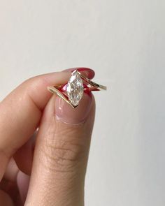 a woman's hand holding an engagement ring with a diamond in the middle and a gold band around it