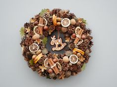 a wreath made out of pine cones and nuts with a ginger house on the top