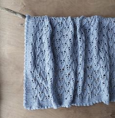 a blue crocheted blanket sitting on top of a wooden table