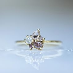 an engagement ring with three different colored stones on it's side, sitting on a white surface