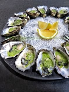 a plate filled with oysters on top of a table next to a lemon wedge