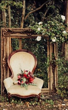 an old chair with flowers on it in front of a mirror and some trees outside