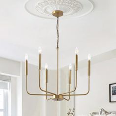 a chandelier hanging from the ceiling in a dining room with white walls and flooring