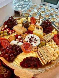 an assortment of cheeses, crackers and grapes on a platter at a buffet