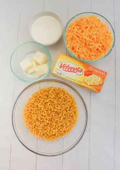 the ingredients to make macaroni and cheese are shown in bowls on a white table