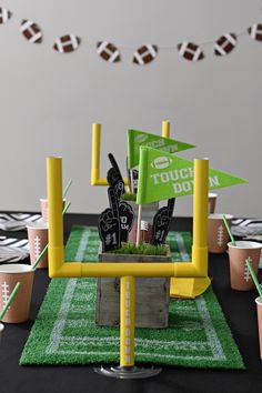 a football themed party with green and yellow decorations on a black tablecloth covered field