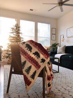 a living room with a couch, chair and christmas tree on the rug in it