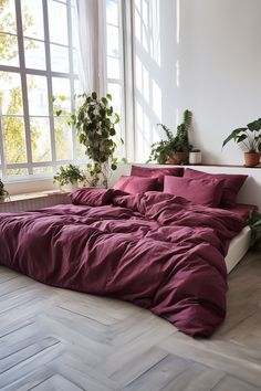 the bed is made up with red sheets and pillows, along with potted plants