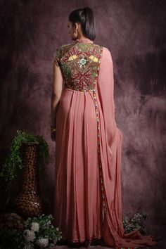 Dusty pink saree gown with pleated collar and extended shoulders embellished with floral and geometric sequin bead work and attached shoulder drape.
Components: 1
Pattern: Embroidery
Type Of Work: Sequin, Beads
Neckline: Round Collar Neck
Sleeve Type: Cap Sleeves
Fabric: Flat Chiffon , Lining: Cotton and Jersey
Color: Pink
Other Details: 

Attached inner lining
Colorful thread embroidery on border
Length:
Gown(in inches): 57
Occasion: Cocktail - Aza Fashions Pink Chiffon Wedding Gown, Pink Designer Dress With Cape Sleeves, Pink Gown With Intricate Embroidery For Evening, Designer Pink Dress With Cape Sleeves, Pink Evening Gown With Intricate Embroidery, Festive Pink Dress With Cape Sleeves, Embellished Georgette Gown With Traditional Drape, Traditional Drape Embellished Georgette Gown, Pink Chiffon Floor-length Gown