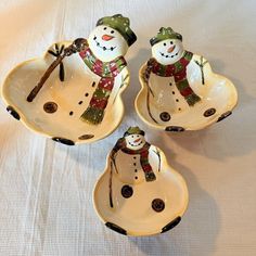 three snowmen are sitting in bowls on a table