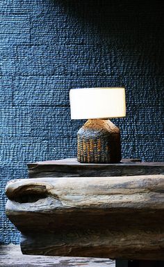 a wooden table with a lamp on top of it in front of a blue wall