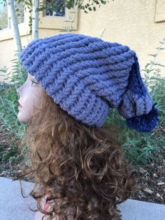 a woman's head with curly hair wearing a blue knitted hat on top of her head